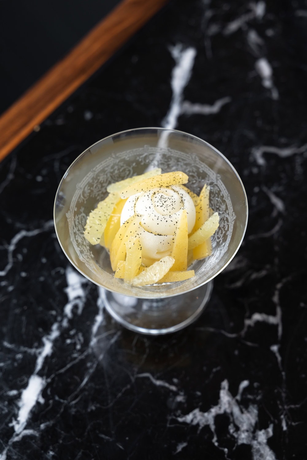 Zitronendessert in einer Glasschale auf schwarzem Marmortisch im Aldabaran