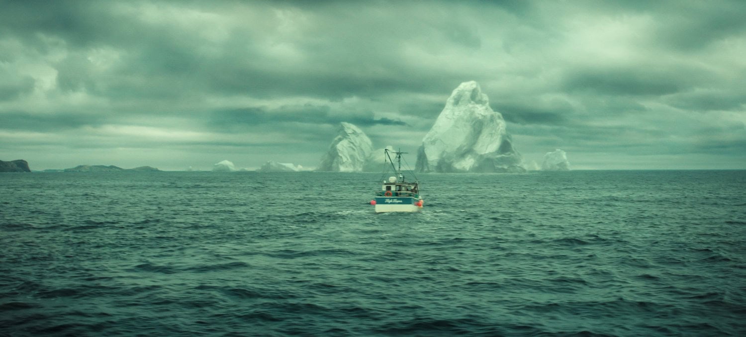 Szene aus »Below«: Ein Fischerboot fährt unter dunklen Wolken auf mehrere große Eisberge vor der Küste zu.