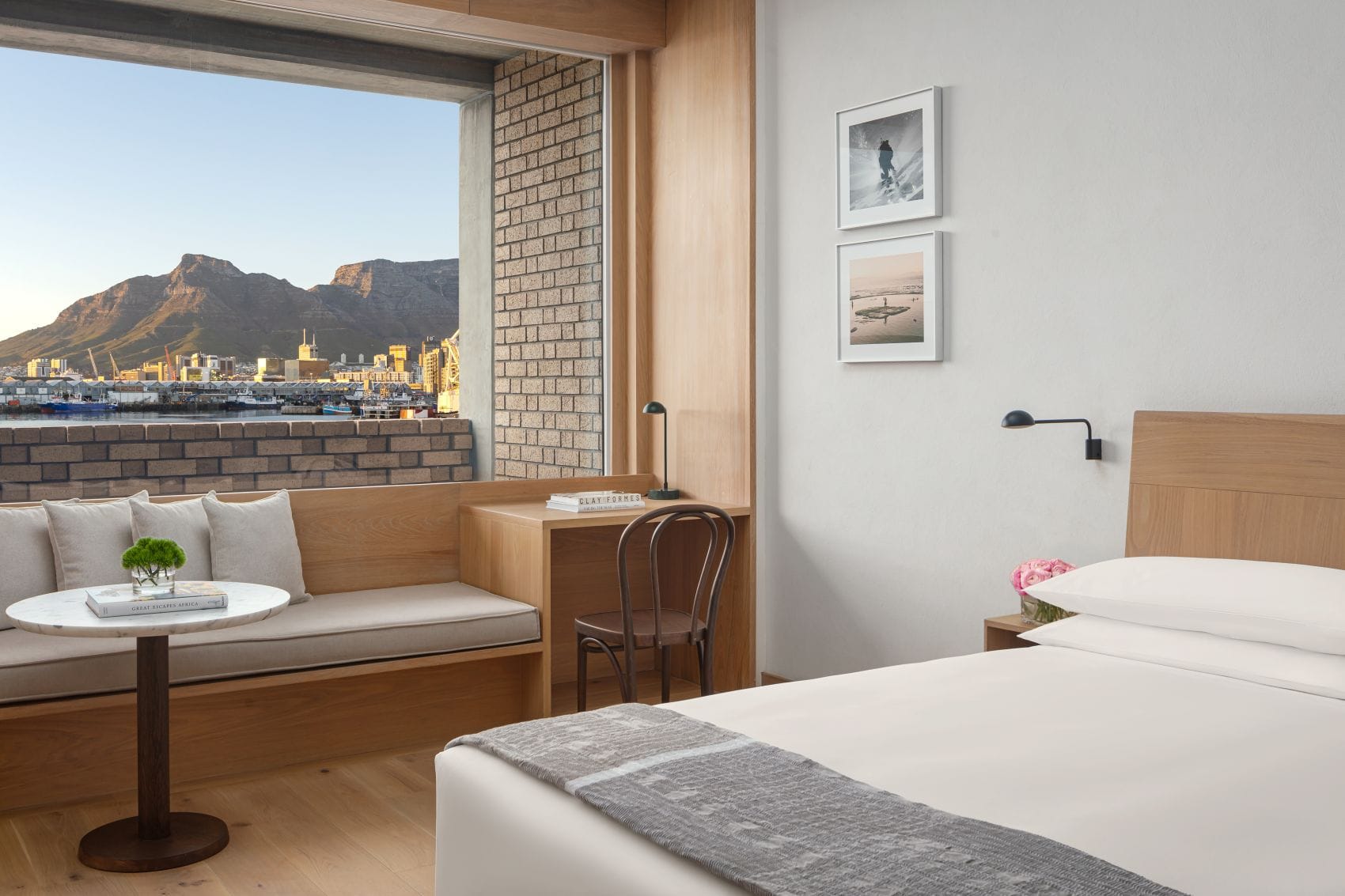 Helles Hotelzimmer im Cape Town EDITION mit Doppelbett, Sitzecke am Fenster und Blick auf den Hafen und den Tafelberg.