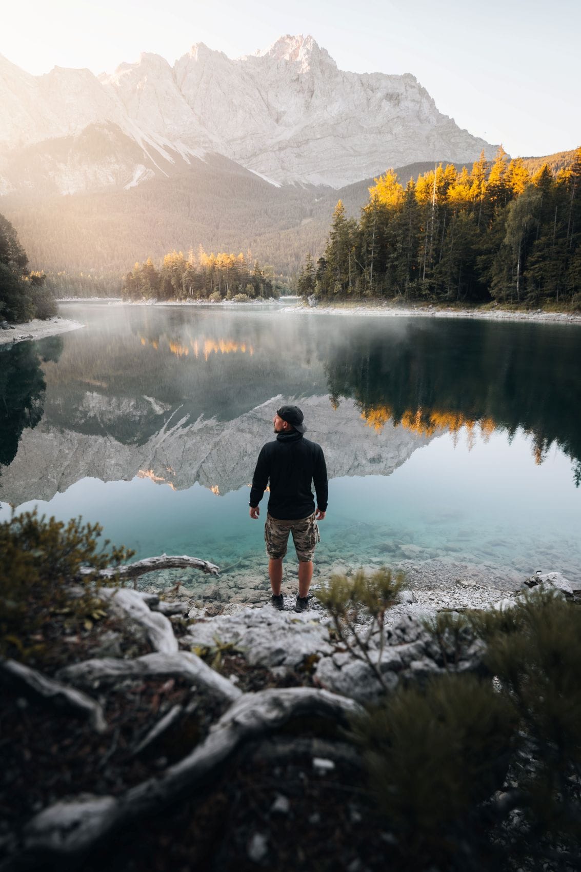Mann am Ufer des Eibsees mit Blick auf die Zugspitze.
