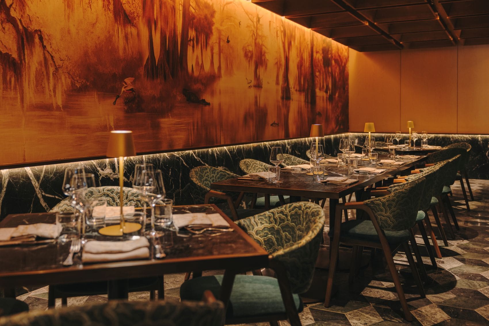 Wine Room des Delmonico Steakhouse im Fairmont New Orleans mit gedeckten Tischen, grünen Polsterstühlen und großem Wandgemälde.