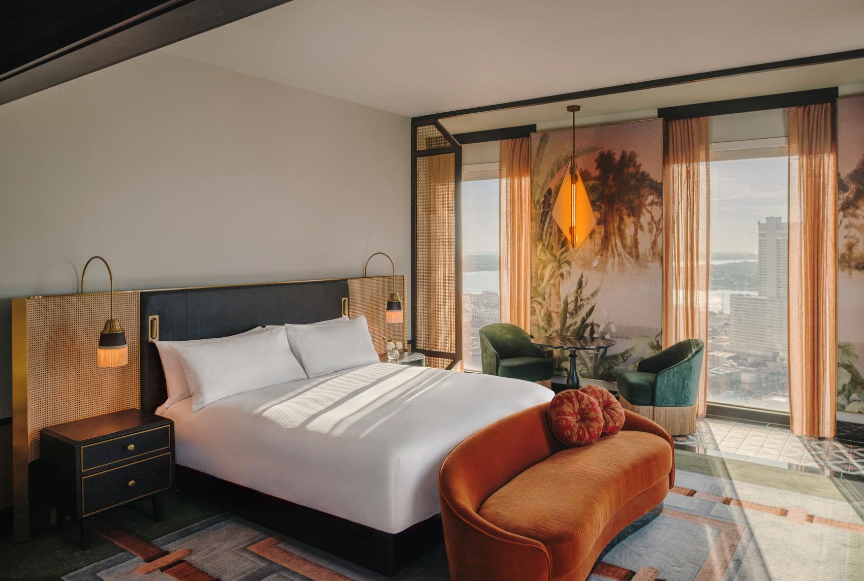 Deluxe River View Zimmer im Fairmont New Orleans mit Doppelbett, orangefarbener Sitzbank und großen Panoramafenstern mit Blick auf den Mississippi.