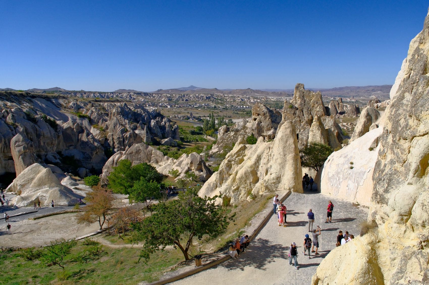 Touristen auf einem Besucherweg zwischen den Felsformationen im Freilichtmuseum Göreme in Kappadokien