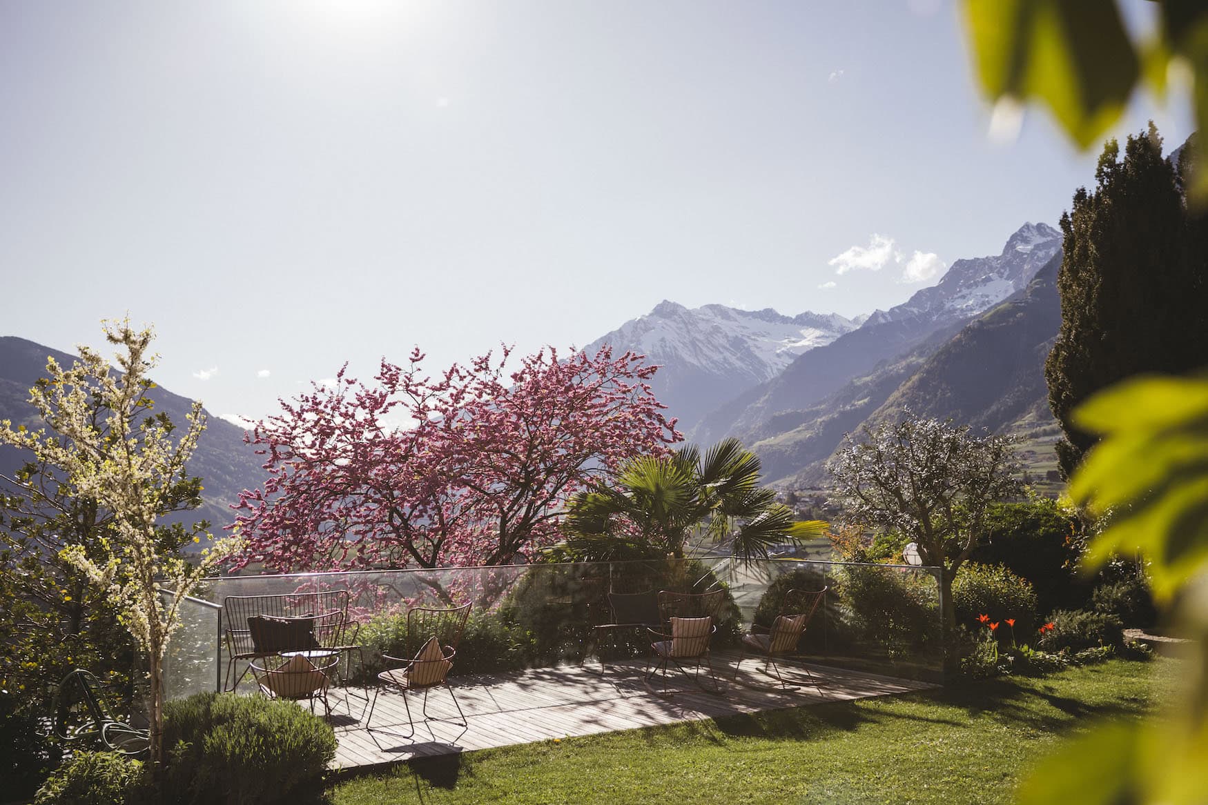 Garten des Hotel Hohenwart mit Terrasse, blühenden Bäumen und Blick auf die Südtiroler Berge.