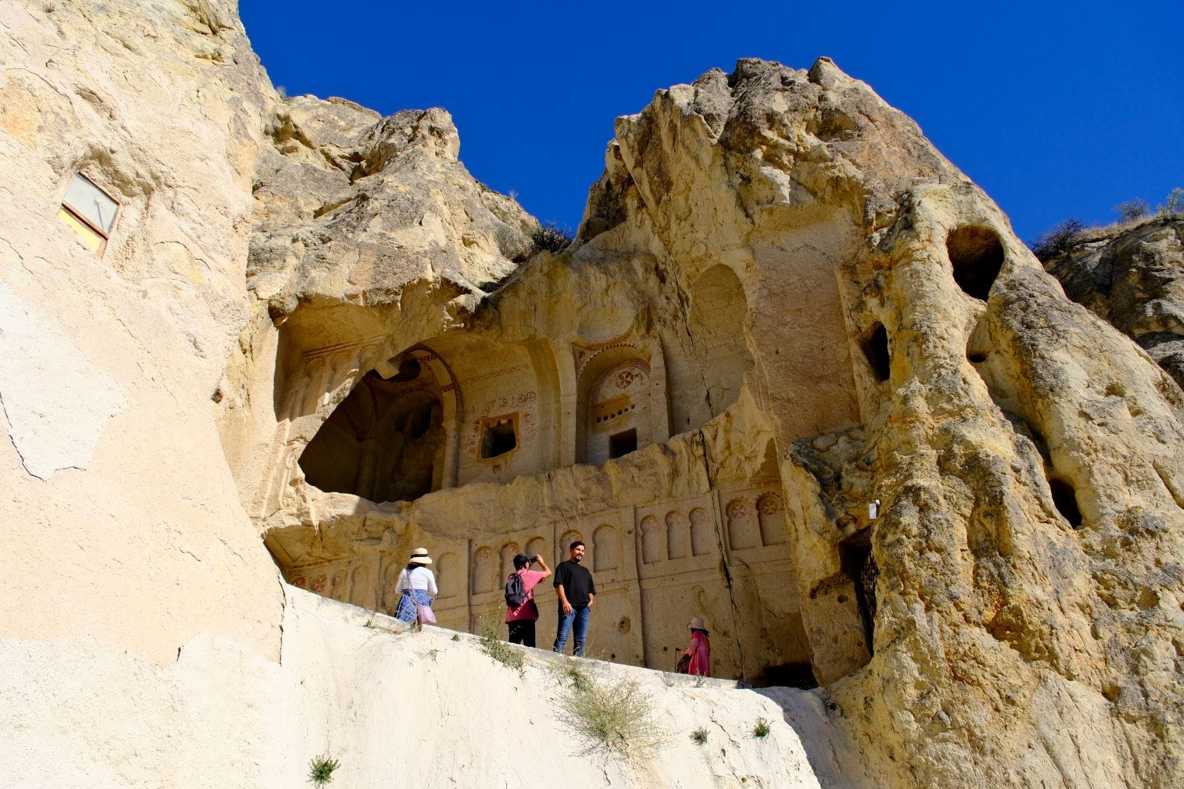 Touristen vor der in den Fels gehauenen Dunklen Kirche im Freilichtmuseum Göreme in Kappadokien
