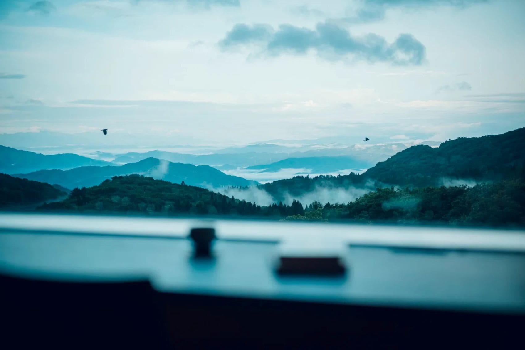Blick vom KAI Zao auf bewaldete Berge und nebelverhangene Täler in der japanischen Präfektur Yamagata