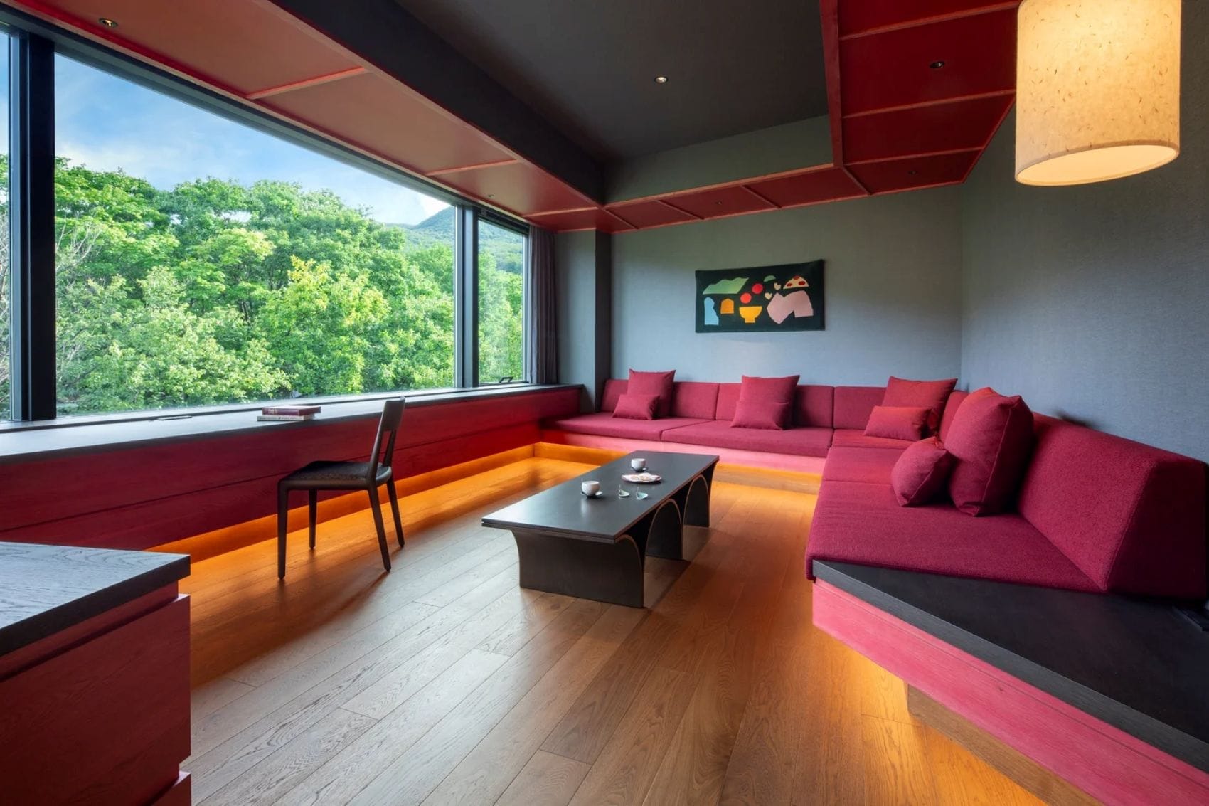 Lounge im KAI Zao in Japan mit roten Polstersofas, Holzboden, modernen Möbeln und großem Panoramafenster mit Blick ins Grüne
