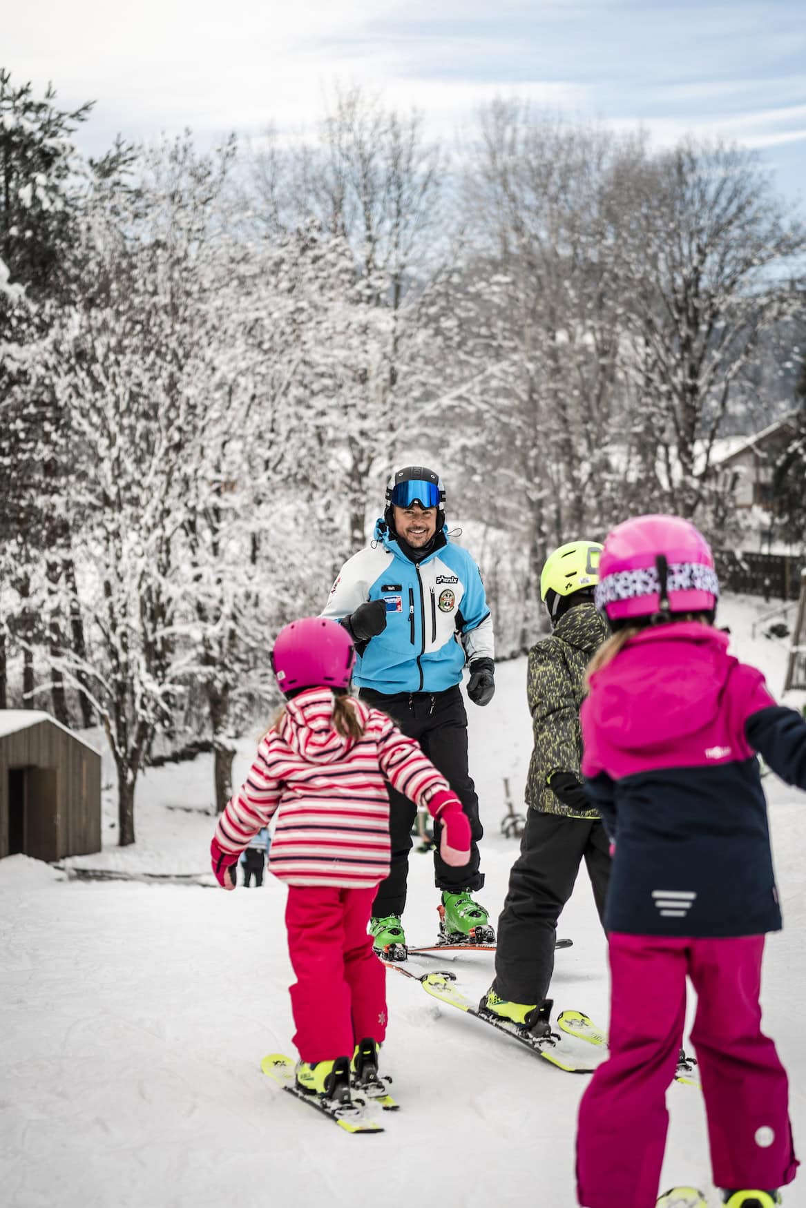 Kinder beim Skikurs mit einem Skilehrer in verschneiter Landschaft im Pustertal.