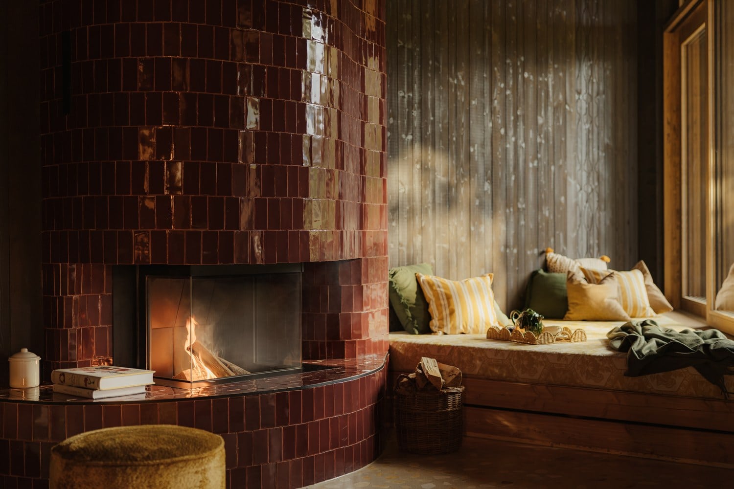 Gefliester Kamin in Bordeauxrot und Sitzfenster mit Kissen in der Himmelsbad-Loge von LaPosch Living Lands
