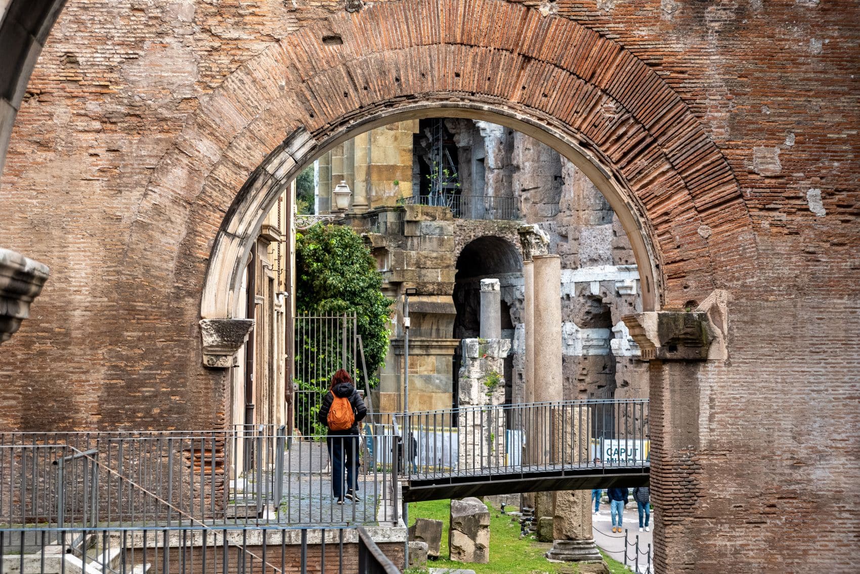 Historischer Ziegelbogen am Portico d’Ottavia in Rom mit antiken Säulen, Mauerresten und Besuchern.