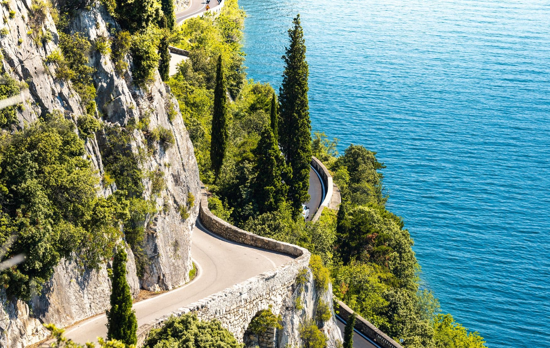 Die Strada della Forra windet sich mit Natursteinmauern und Zypressen an der Felswand über dem Gardasee entlang