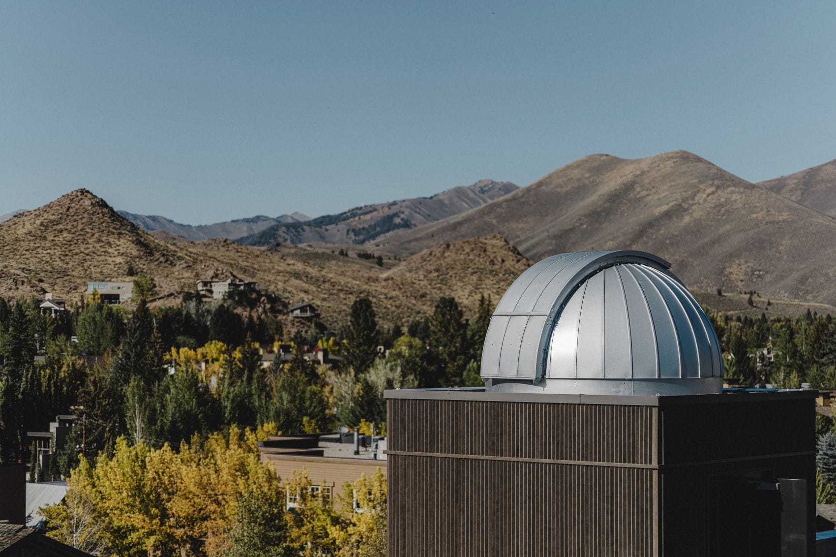 Silberne Kuppel der Sternwarte im The Observatory, A Viceroy Resort, in Idaho vor einer Berglandschaft mit herbstlich gefärbten Bäumen.