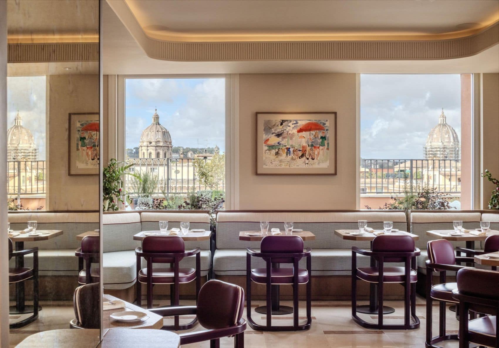 Restaurantbereich im Thompson Rome mit gepolsterten Sitzbänken, dunklen Holzstühlen und Blick auf zwei Kirchenkuppeln.