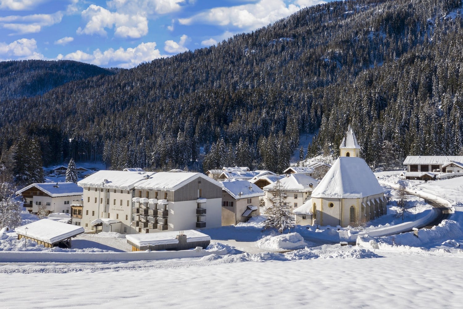 Verschneites Bergdorf Unsere Liebe Frau im Walde mit Hotel und Kirche vor Waldhängen