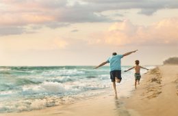 Ein Mann und Kind laufen am Strand in Fort Myers entlang
