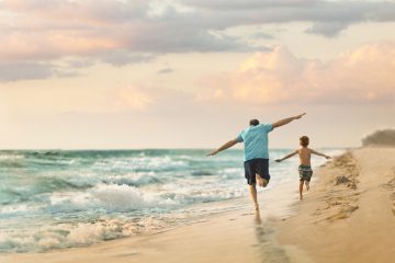 Ein Mann und Kind laufen am Strand in Fort Myers entlang