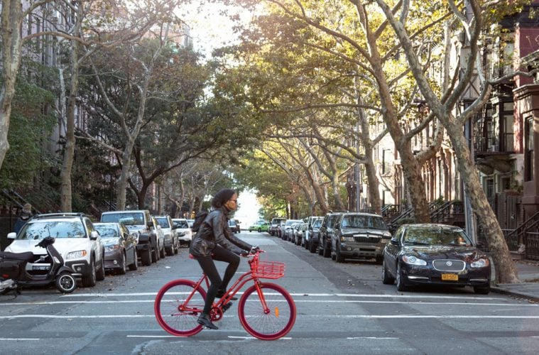 Ein Afroamerika fährt auf einem roten Fahrrad auf einer Straße in Brooklyn